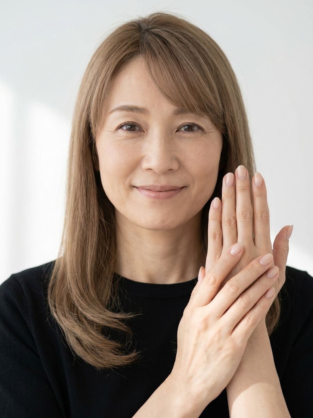 手の甲をそっと見せて微笑む50代の女性（イメージ）