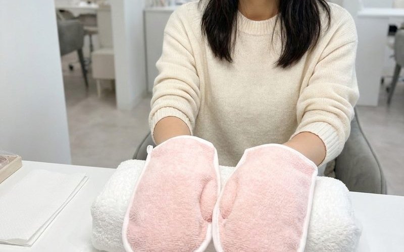 パラフィンパックをした両手を、ピンクのミトンで包んでいる