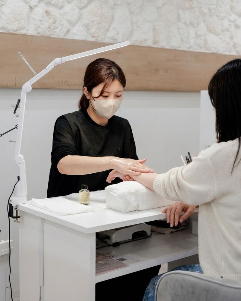 ネイリストが手首から腕へ、オイルでトリートメントしている
