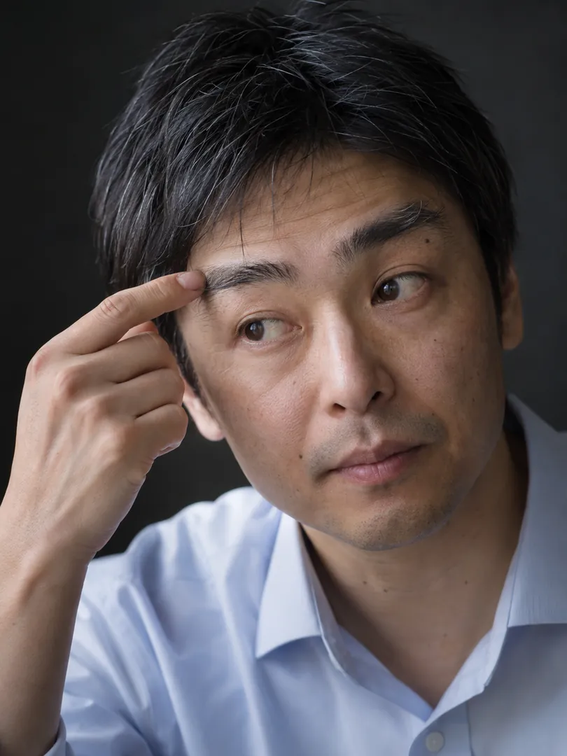 伸びた眉毛に指で触れる40代男性のイメージ