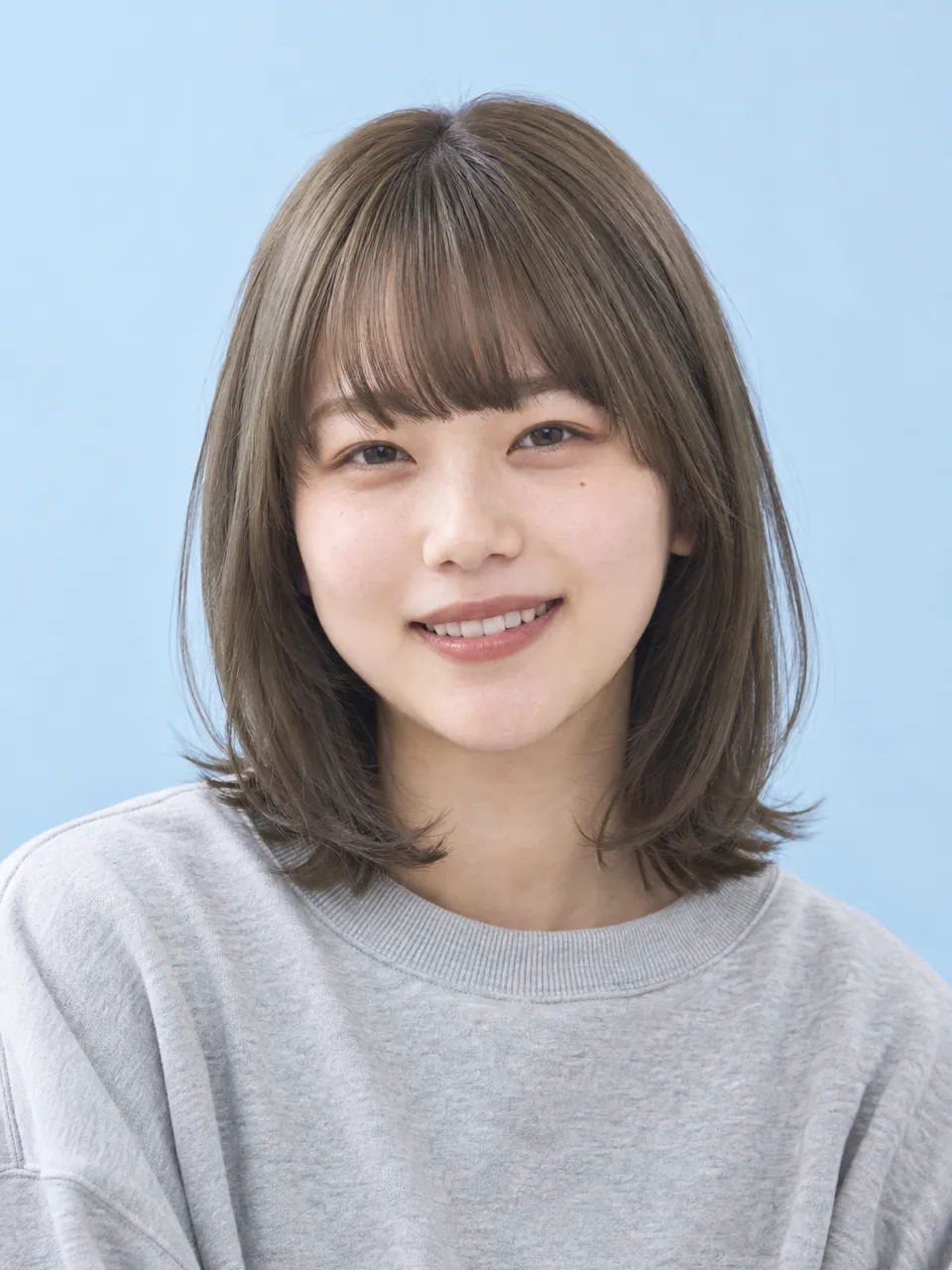 ミントブラウンの髪色で、スウェット姿の20代女性のイメージ
