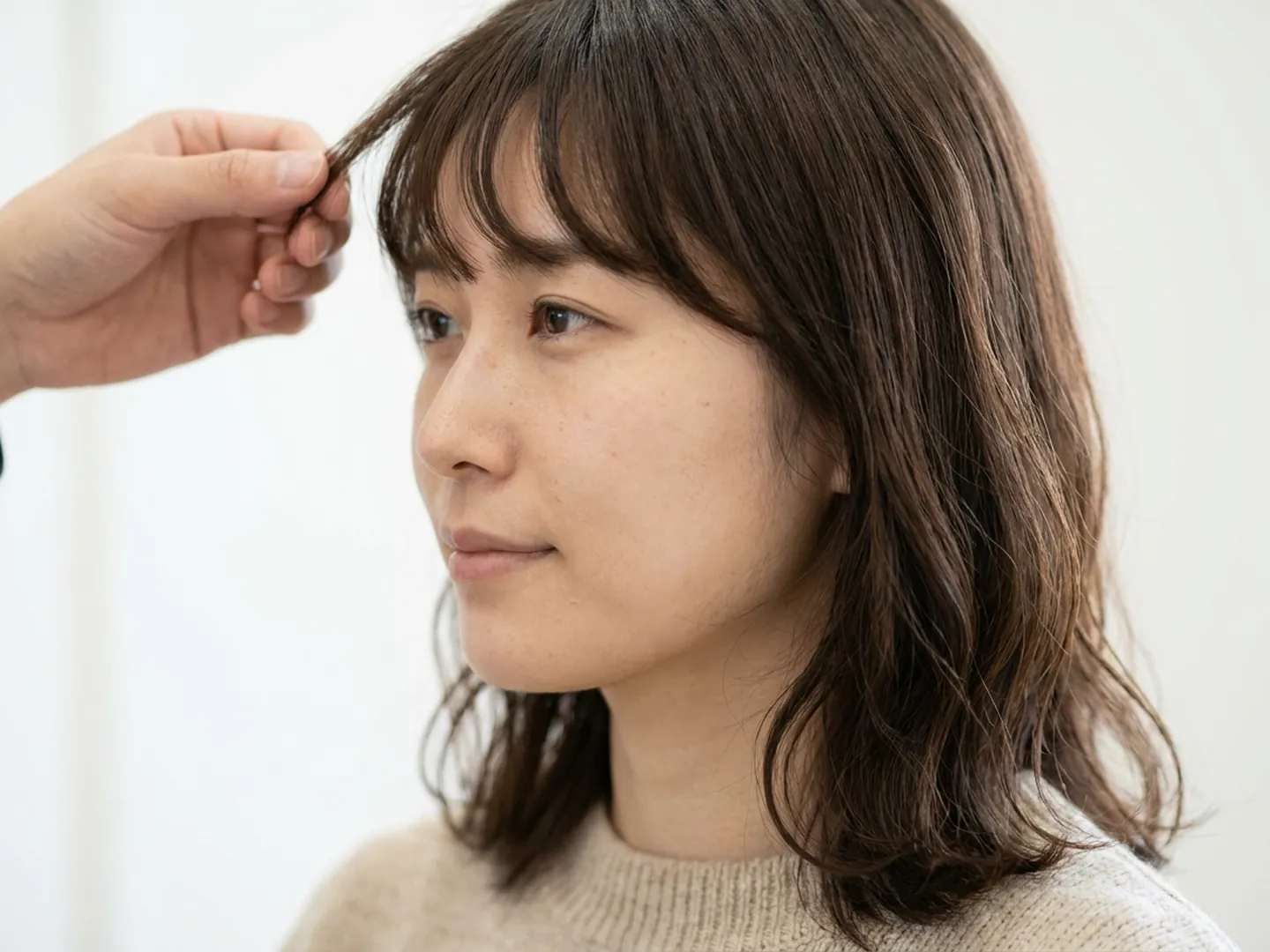 施術の前に、前髪のうねりを指で確かめる相談のイメージ