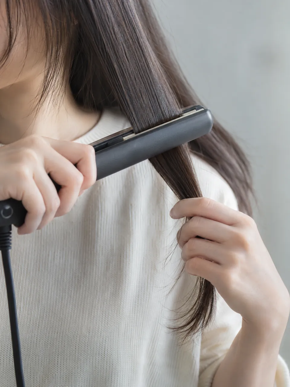 朝、ヘアアイロンで横の髪を挟む手元のイメージ