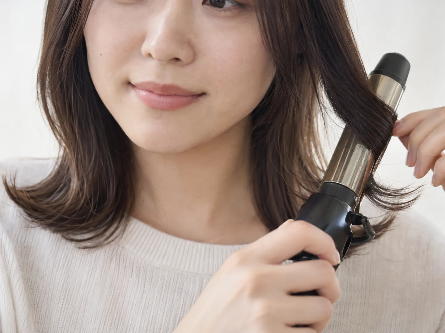 朝、コテで毛先を外にはねさせる手元のイメージ