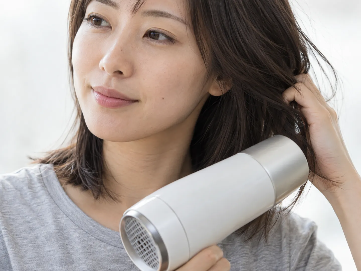 朝、ドライヤーで髪を乾かす手元のイメージ