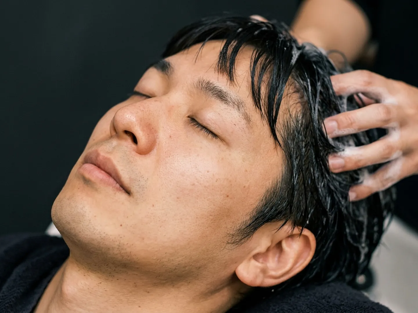 目を閉じてヘッドスパを受ける男性のイメージ
