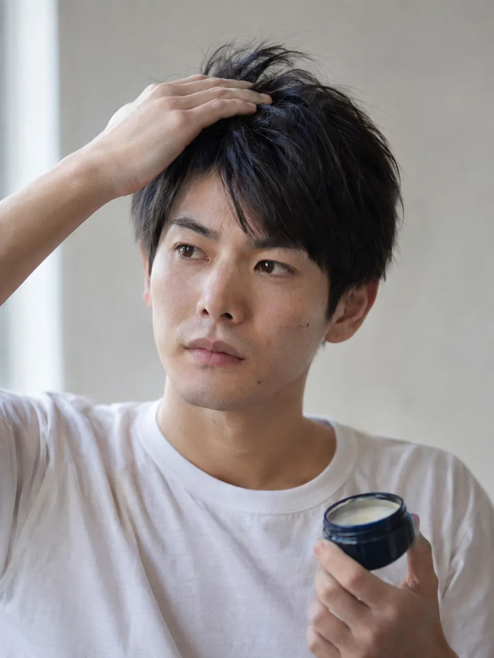 朝の洗面台で寝ぐせのついた髪に手をやる男性のイメージ