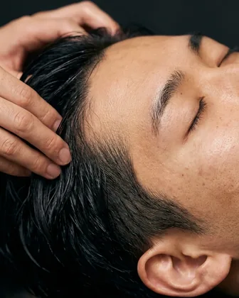 仰向けで目を閉じ、指の腹で頭皮を押されるスキャルプスパのイメージ